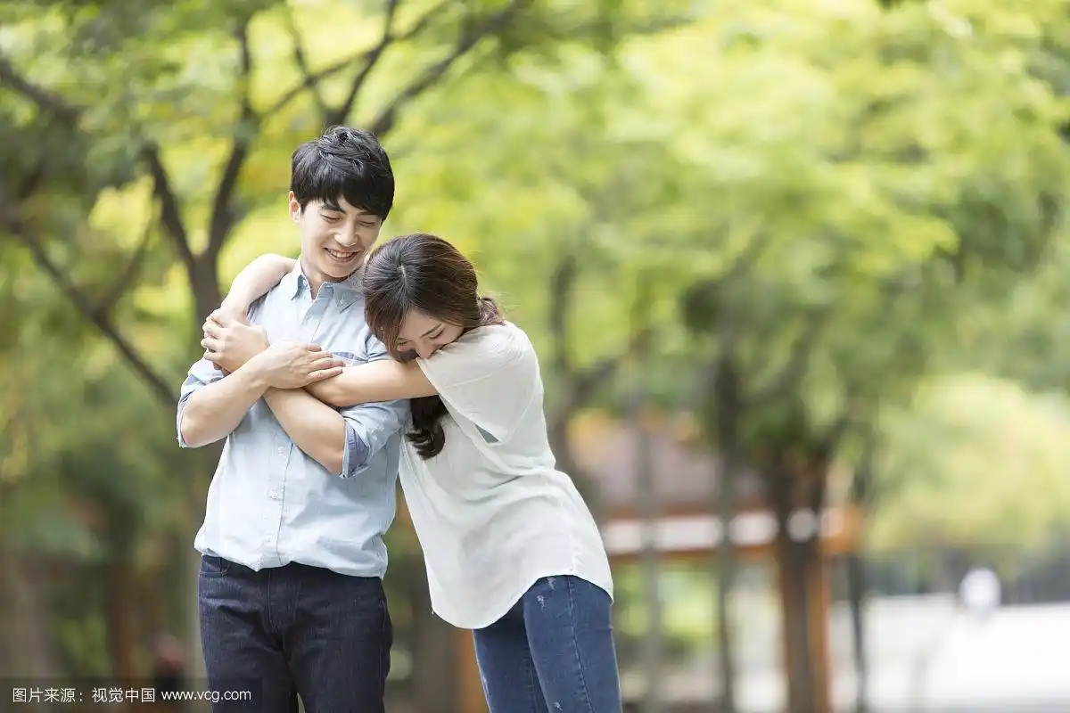 穿着休闲服装的情侣在公园街道上拥抱的照片