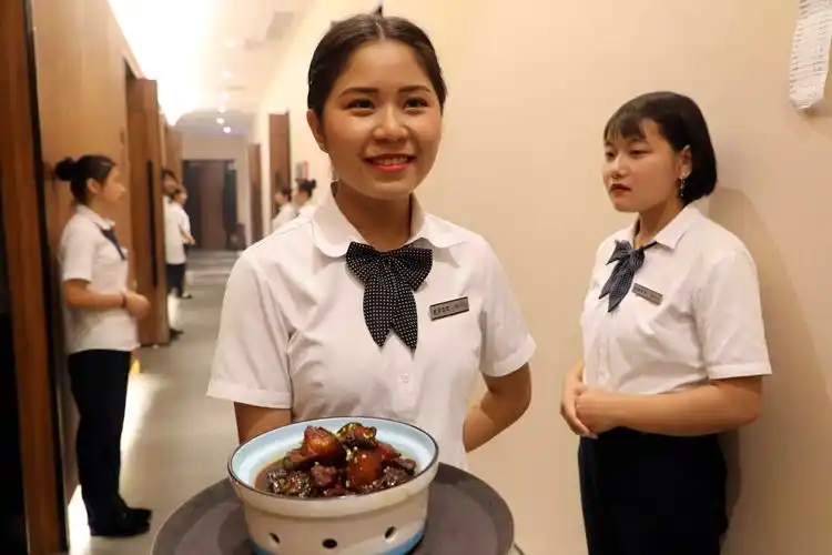 餐厅中一位美女服务员正端着美食准备上菜,这里不仅环境优雅,佳肴鲜美