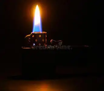 金属金色打火机在黑暗的背景下点燃火焰照片