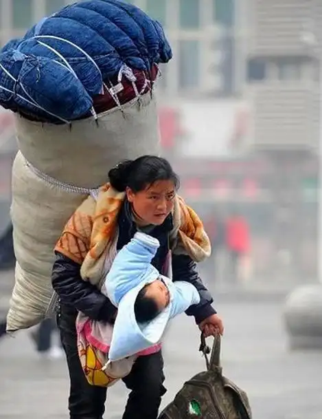 着沉重的包袱,手里提着包包,右手还抱着年幼的孩子,伟大的母爱能让一