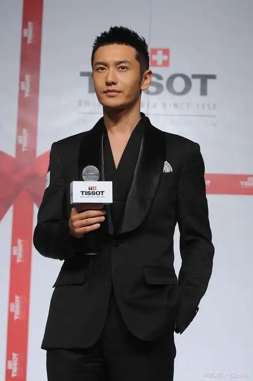 照片中,黄晓明身穿一身黑色西装,站在悬崖边,背景是壮丽的山水景色,给