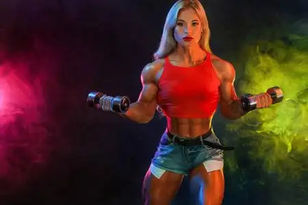 女冠军强壮的女健美运动员冠军,深色背景上有哑铃,穿着运动服.