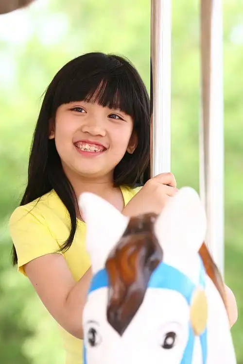 一个小女孩在户外玩旋转木马图片下载