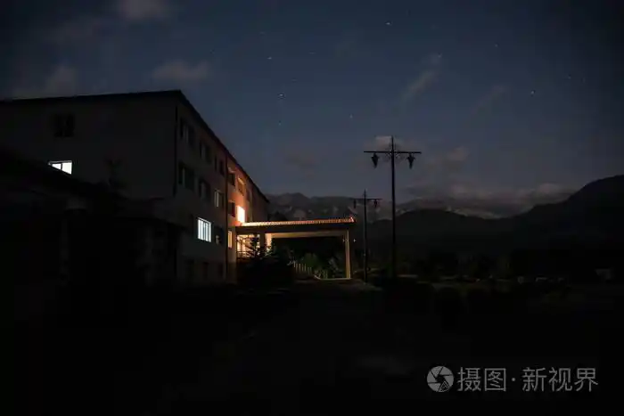 晚上在森林里建筑的山夜风景与月亮或老式乡下房子在晚上与云彩和星.