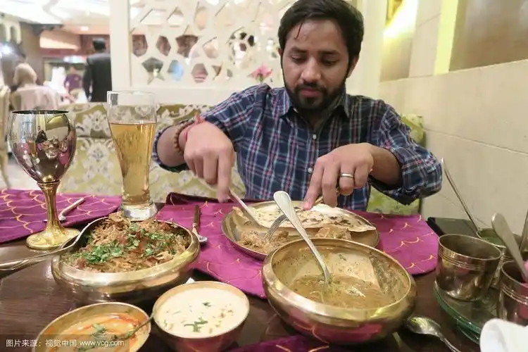 印度男子在印度餐厅的餐桌上吃晚餐的照片,lucknowi鸡肉biryani,肉汁