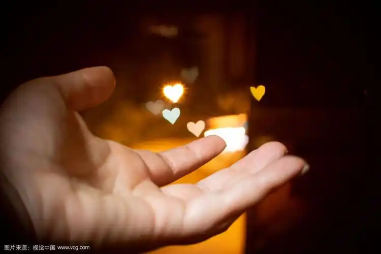 一只手伸着,背景是心形的灯