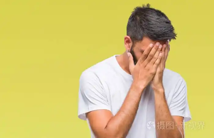 成年西班牙裔男子在孤立的背景上悲伤的表情覆盖着脸双手哭泣抑郁的
