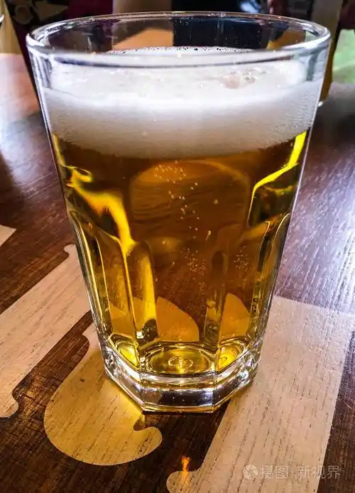 特写镜头的啤酒,木制的桌子上的杯子.啤酒的宏