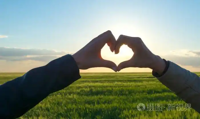 浪漫的情侣在日落打手势用手指一颗心的爱