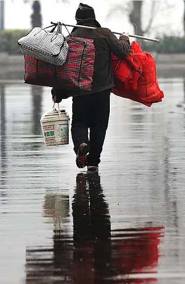 1月21日一位旅客背着行李在雨中走向南京火车站候车大厅春运大幕即将
