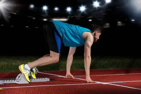 起跑点短跑运动员在大现代体育场前面的跑道上, 带着灯光离开起跑点.