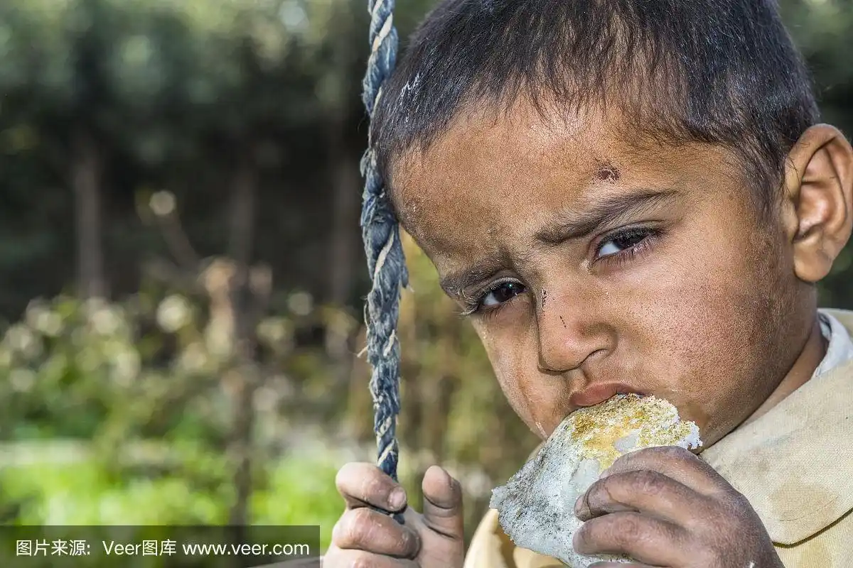 一个贫穷的盯着饥饿的孤儿男孩在难民营的特写,他的脸上有悲伤的表情
