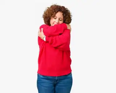 美丽的中间年龄更高的高级女人红色冬季毛衣在孤立的背景下拥抱自己