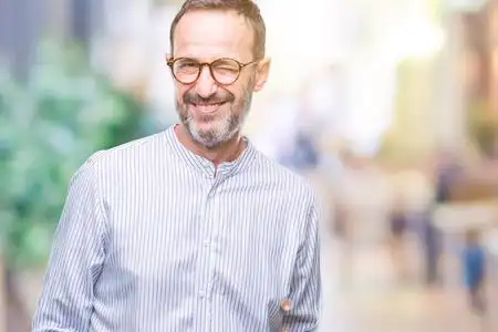 中年老人戴着眼镜,在孤立的背景下眨眼,看着镜头,的表情,开朗和快乐的