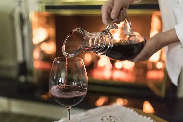 一个面面相觑的女人,手里拿着酒瓶,往杯子里倒红酒.图片下载