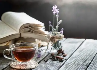 一杯茶,里面有一本书,里面有淡紫色的花,在一个透明的花瓶里,在一个