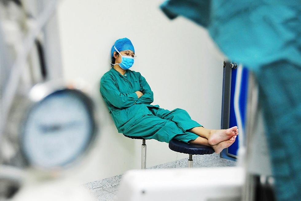 图为广州某医院,一名护士小姑娘在两台手术的间隔中,累得趴在椅子上