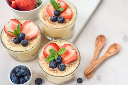 自制提拉米苏自制, 精致的甜点提拉米苏在眼镜装饰与草莓, 蓝莓, 薄荷