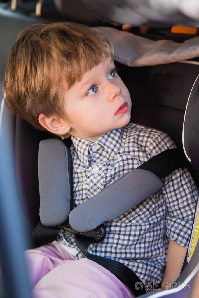 那个可爱的小男孩坐在婴儿车的座位上坐在车里看着一边