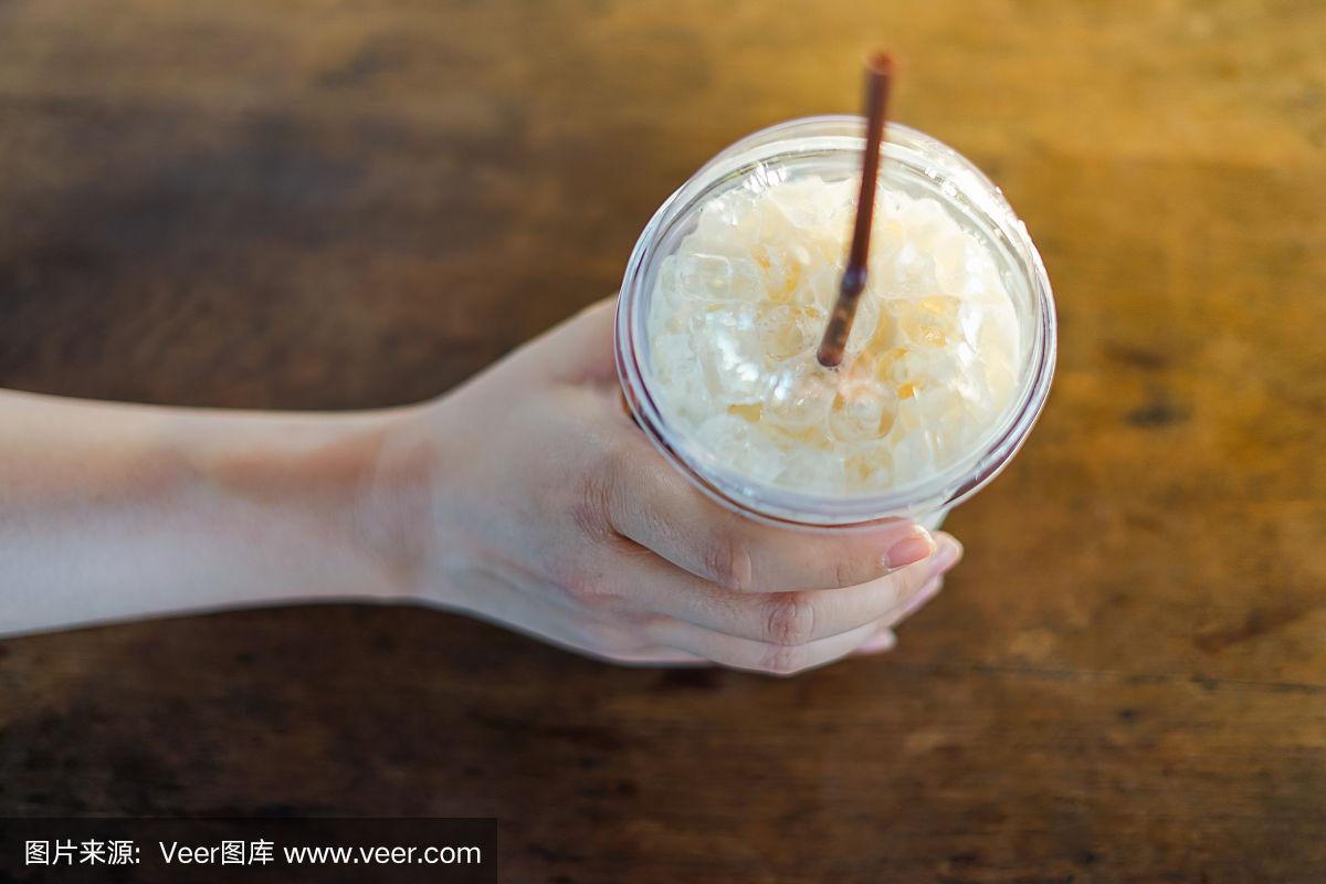 手拿一杯冰牛奶放在桌子上