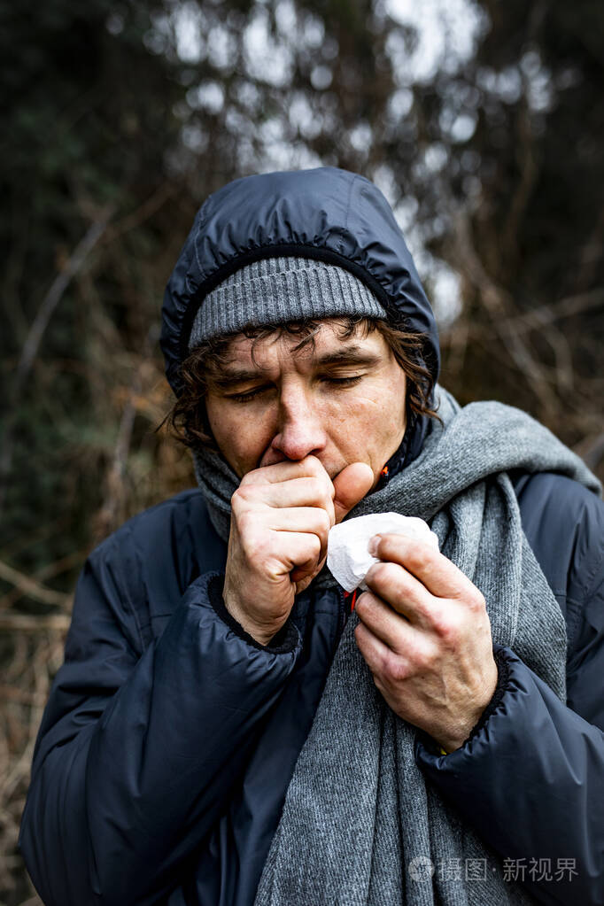 多云寒冷的日子里一个生病咳嗽的男人走在街上流感季节感染