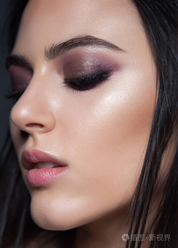 特写美女肖像.深色的紫色化妆.黑色背景的魅力女人.发光的皮肤