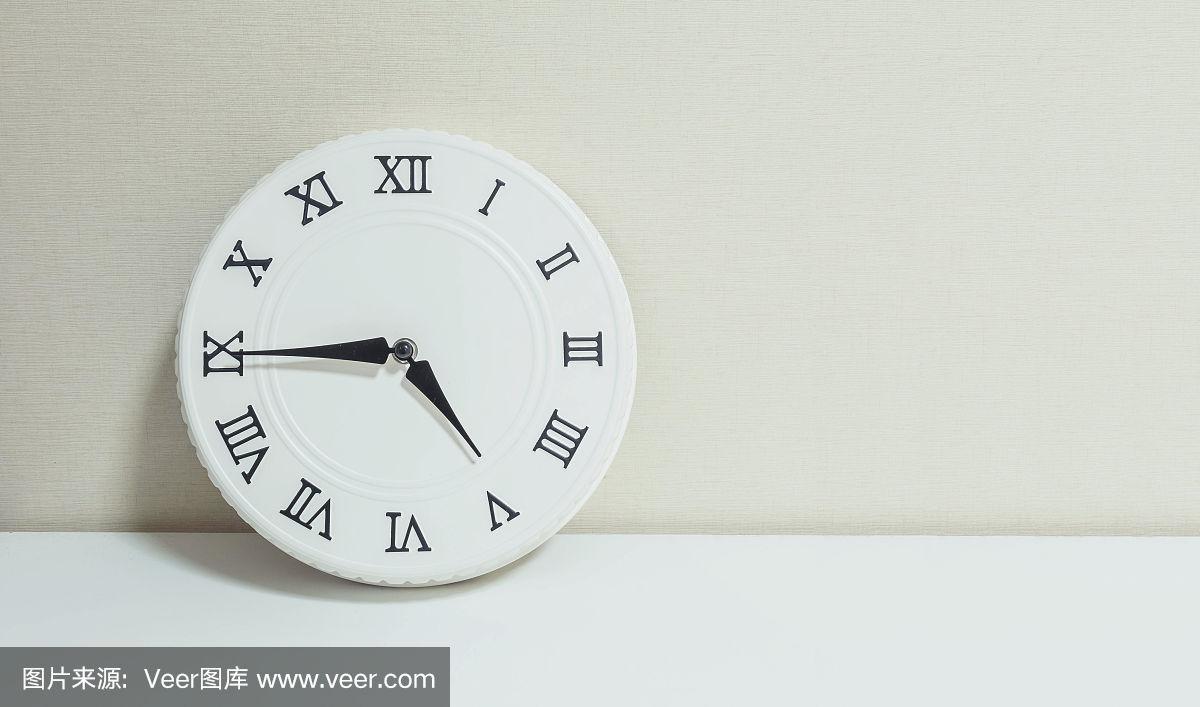 近距离白色时钟装饰显示下午四刻钟或下午四点四十五在白色木质桌子和