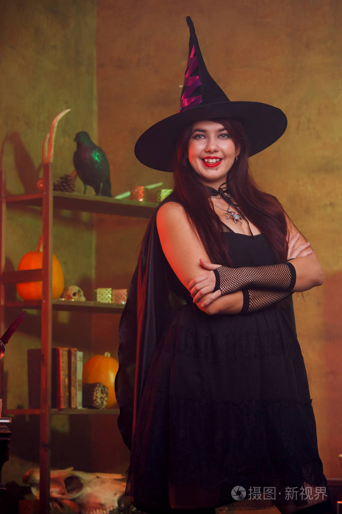 女巫的肖像在黑色礼服和帽子在魔术房间照片-正版商用图片0tdky1-摄图