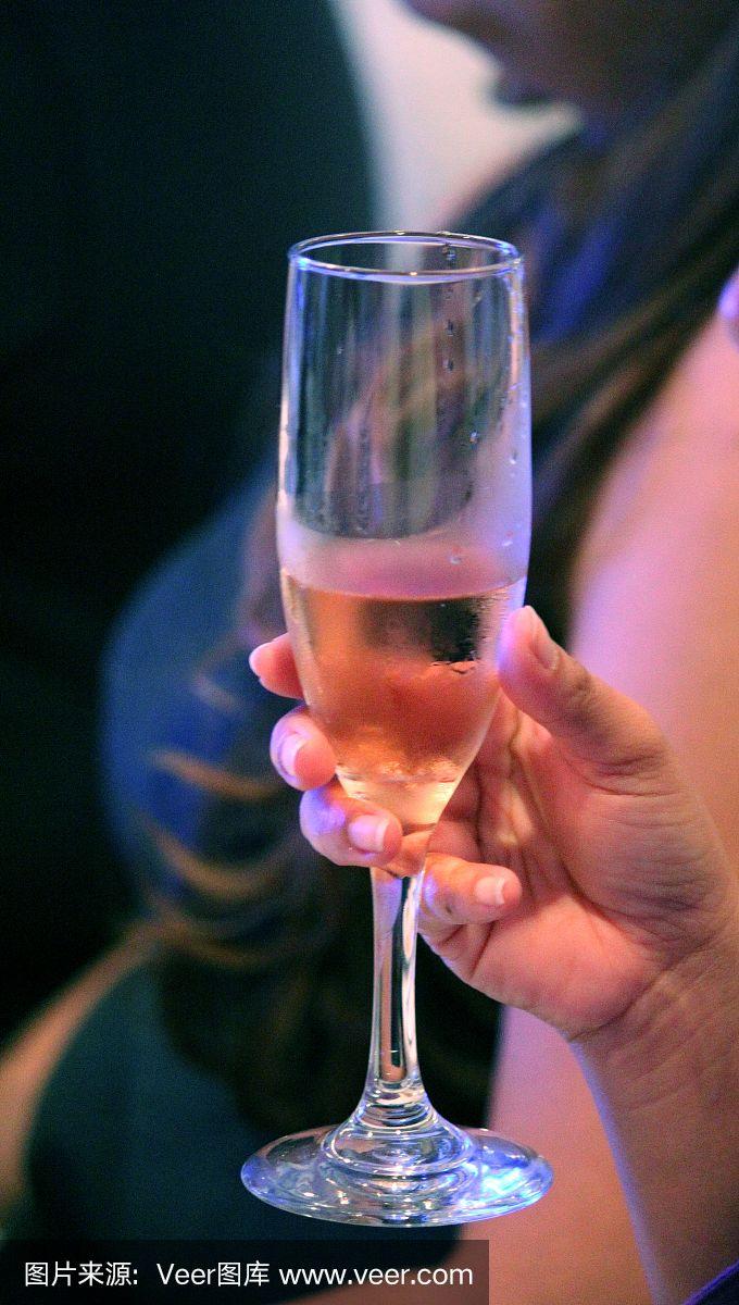 手里拿着一个装着白葡萄酒的高脚杯