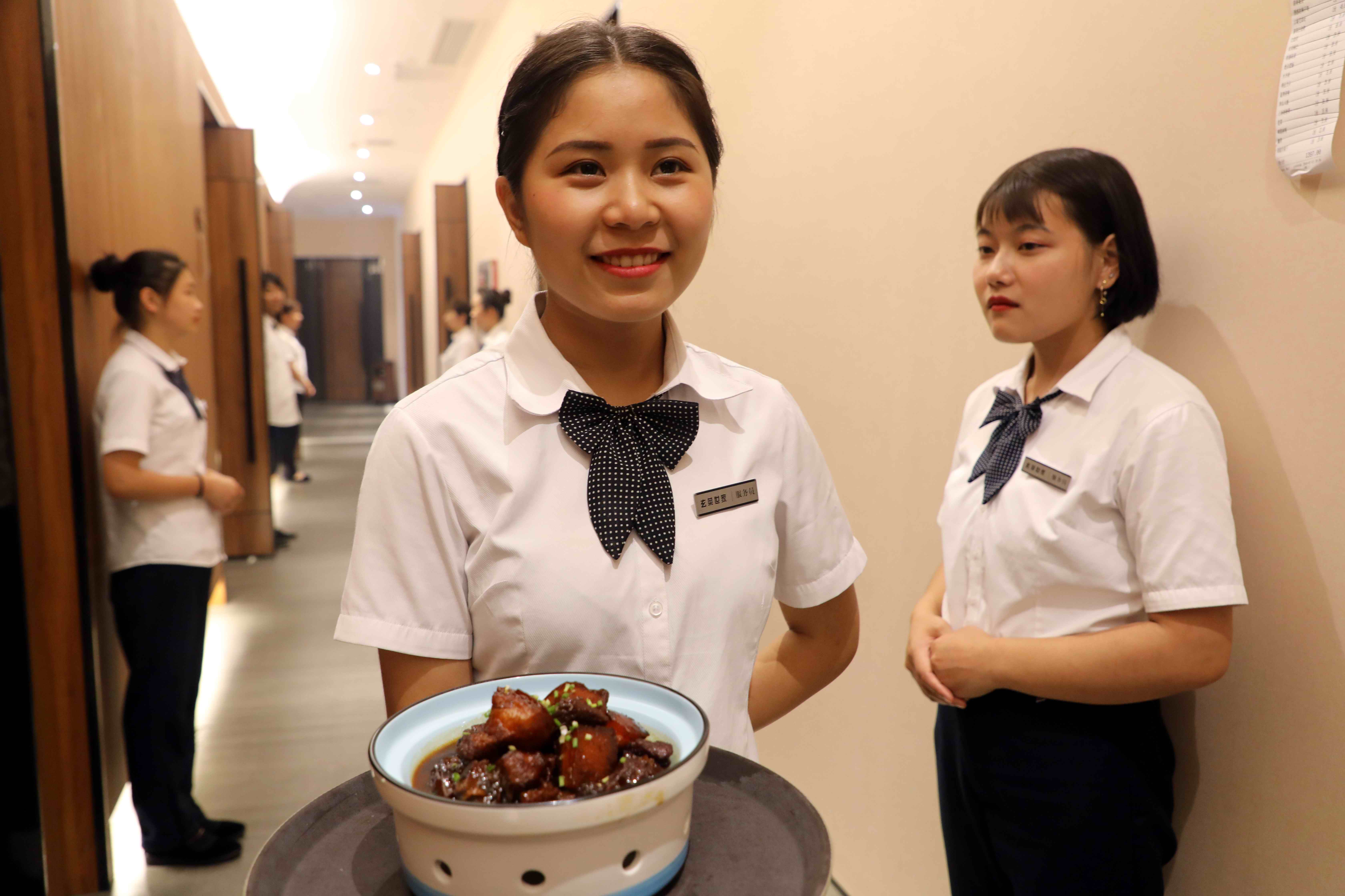 餐厅中一位美女服务员正端着美食准备上菜,这里不仅环境优雅,佳肴鲜美