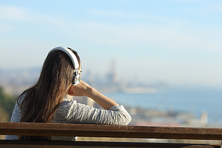 一个放松 i>的 /i>女 i>人 /i>戴着耳机听音乐,思考城市郊区景色 i>的