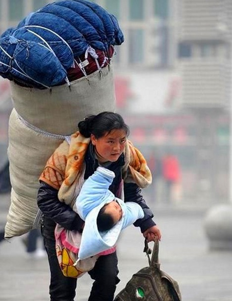着沉重的包袱,手里提着包包,右手还抱着年幼的孩子,伟大的母爱能让一