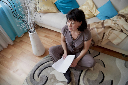 夫人与调情的表达客厅里的中年妇女很好.夫人在家与纸照片