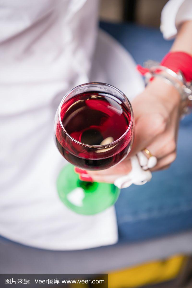 美丽的女性手握红酒杯在灯光背景