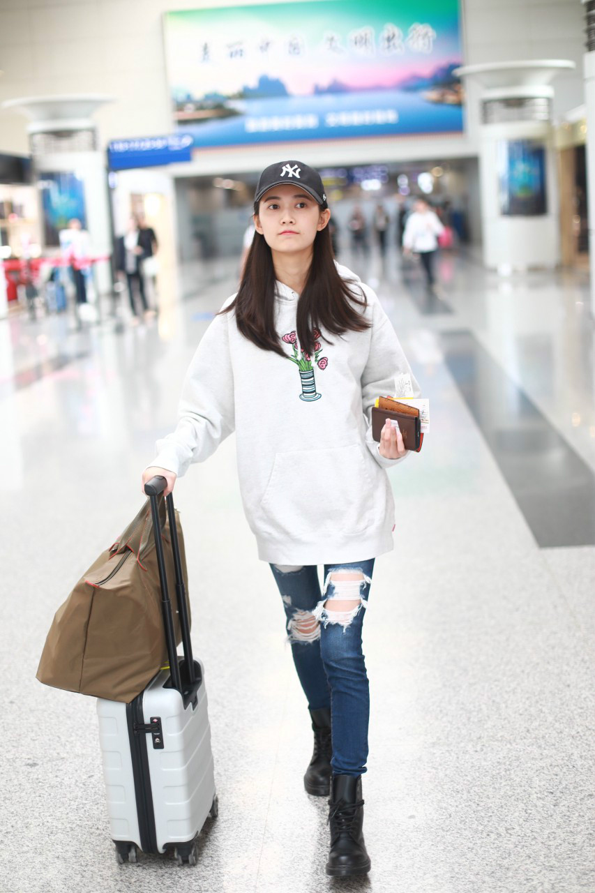 陈钰琪穿白色卫衣搭配破洞牛仔裤现身机场,戴黑色棒球帽皮肤白皙