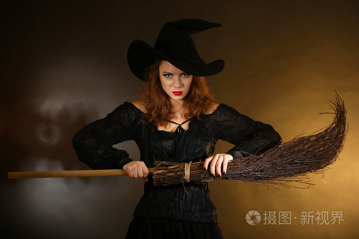 万圣节女巫用扫帚在深色背景上