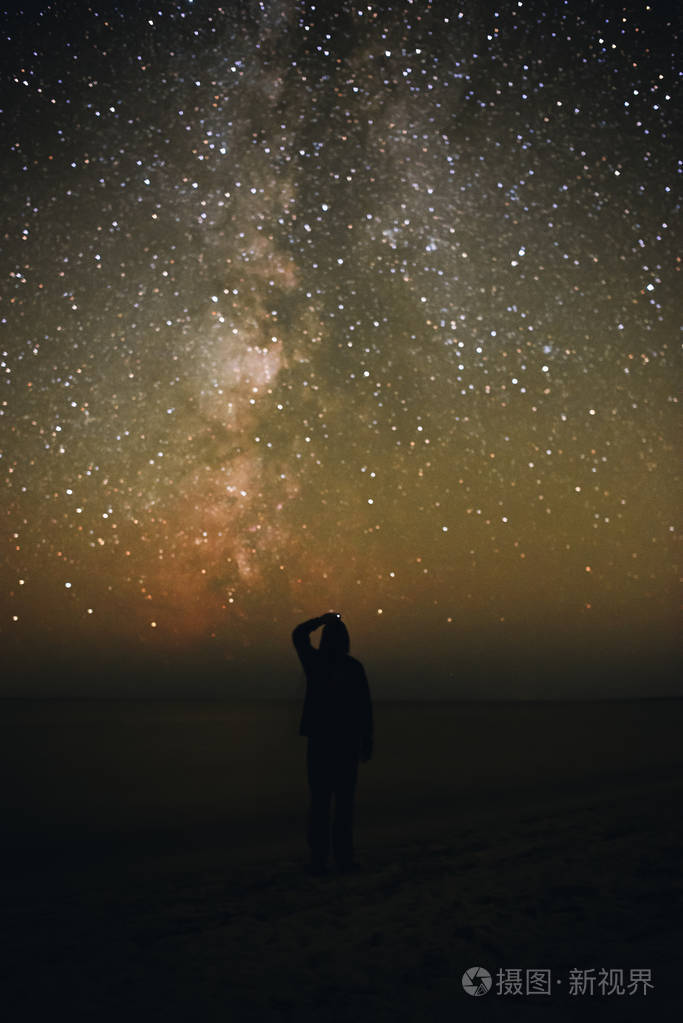 一个孤独的男人的剪影站在海边, 看着星空与银河