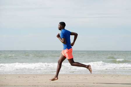 奔跑侧面健康的非裔美国人在海滩上奔跑的全身侧面肖像照片