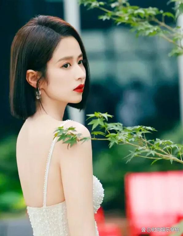 颖儿,一个穿着白色吊带裙,展现窈窕曲线的美丽女孩,她短发及肩,回眸