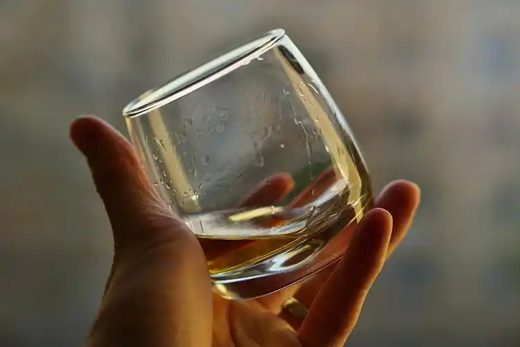 男手拿着一个金色的威士忌酒杯图片下载