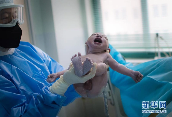 3月1日,在武汉市妇幼保健院,助产士将新出生的宝宝抱给产妇看.
