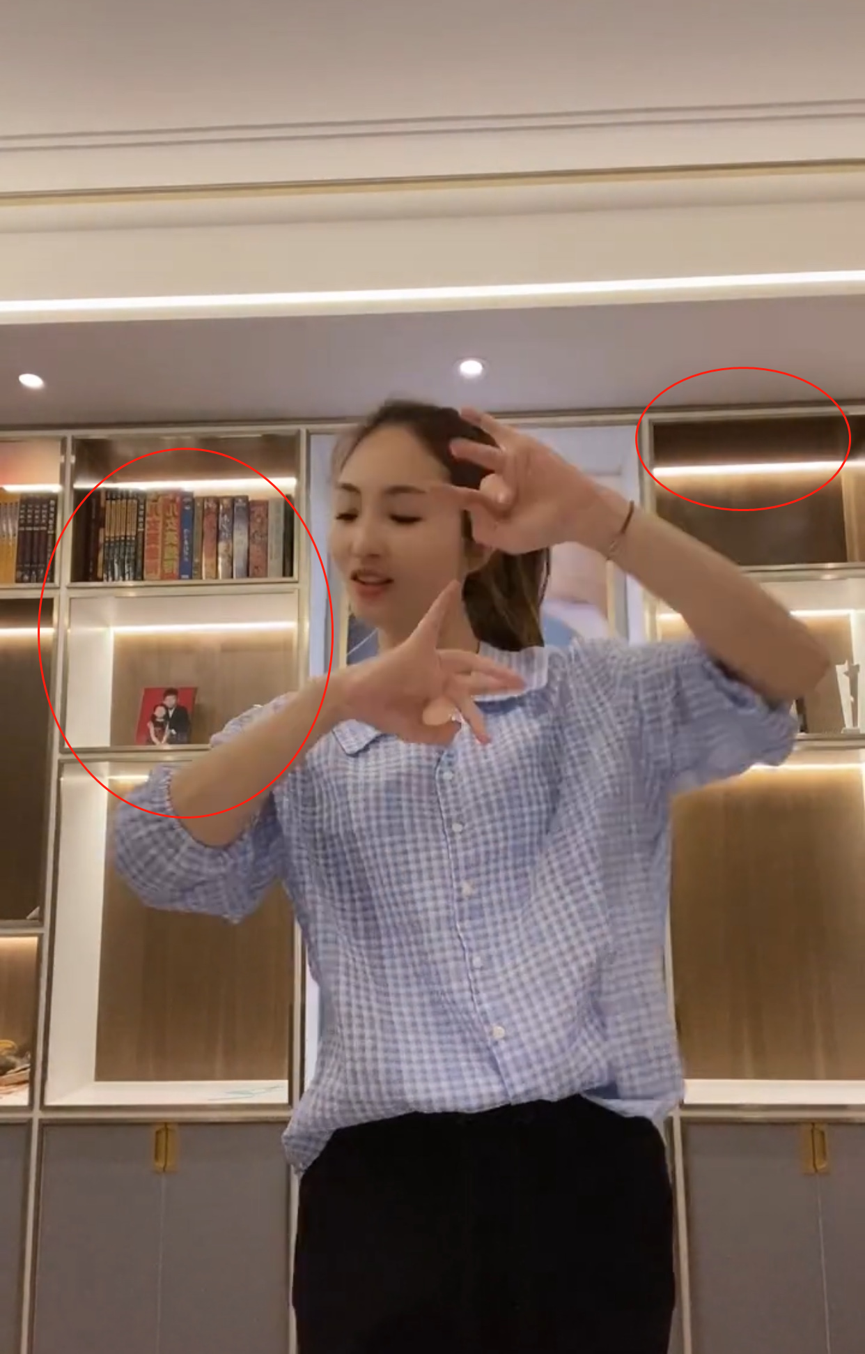 视频中,李汶桐穿着蓝白格子上衣正在跳舞,身后的巨大柜子上都装满了灯