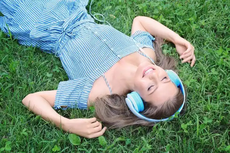 躺在绿色草地上听音乐耳机的女人放松放松
