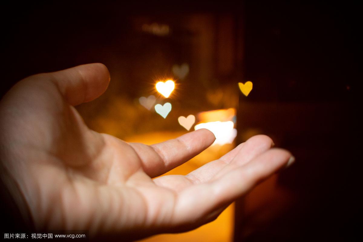 一只手伸着,背景是心形的灯