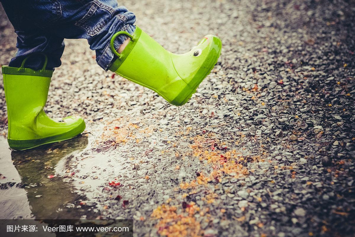 雨靴踩在一个孩子的脚上,踩在泥坑里