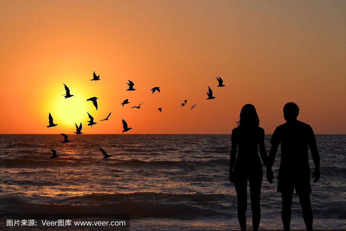 一对夫妇的剪影牵手看日出在海滩上