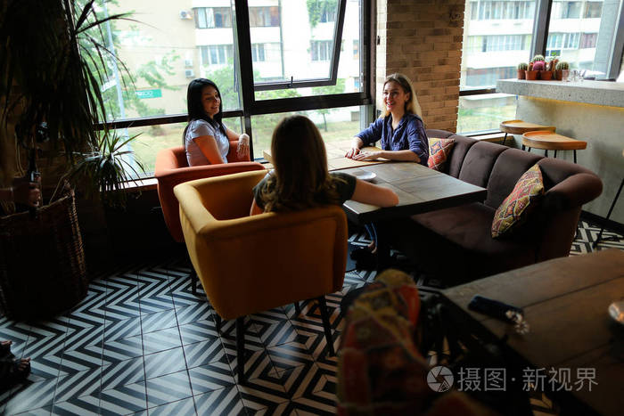 女孩坐在舒适的咖啡馆微笑和喝咖啡