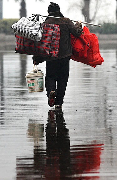 1月21日一位旅客背着行李在雨中走向南京火车站候车大厅春运大幕即将