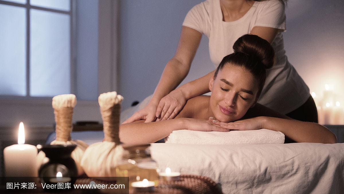 女人接受背部按摩,享受水疗晚上