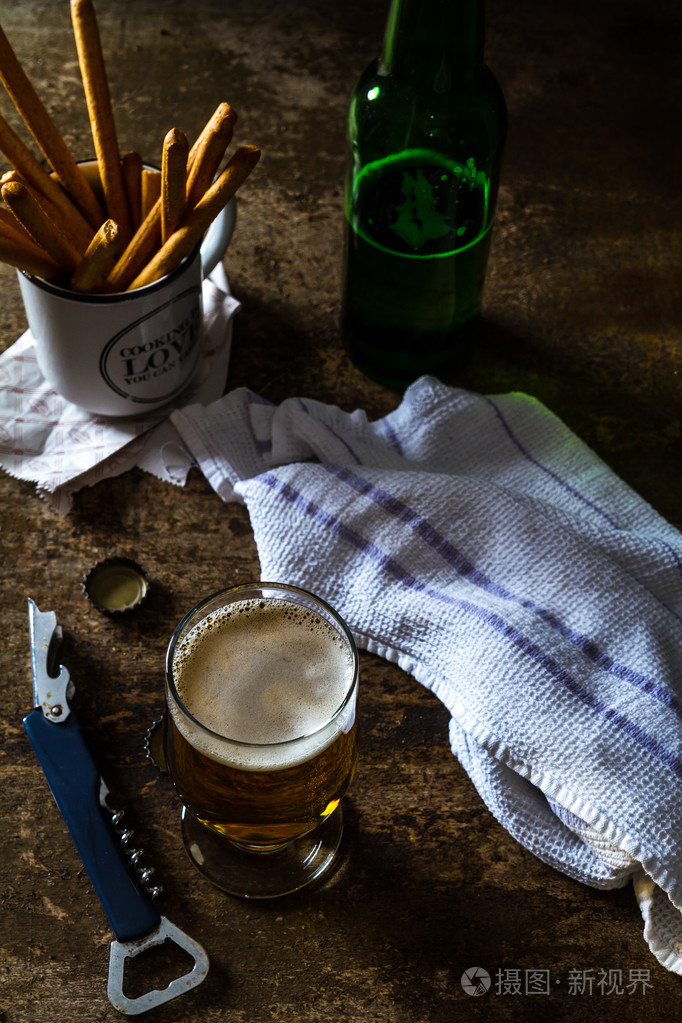 杯光啤酒与小吃的暗棕色的桌子上